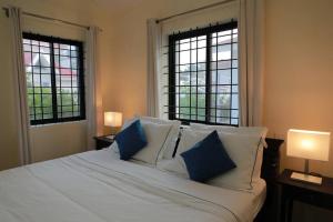 - une chambre avec un grand lit blanc et 2 fenêtres dans l'établissement Tranquil Staycation - Independent Duplex House, à Hosur