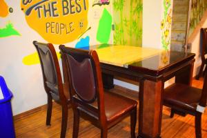 een tafel en stoelen in een kamer met een bord aan de muur bij Prince Solo Hostel in Mumbai