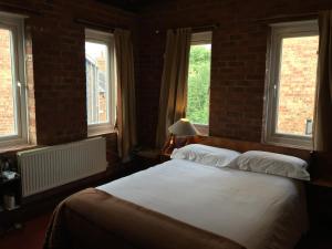 a bedroom with a large bed with two windows at The Jericho Hotel in Oxford