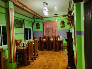 ein Esszimmer mit grünen Wänden sowie einem Tisch und Stühlen in der Unterkunft BANAUE EVERGREEN HOSTEL AND RESTAURANT in Banaue