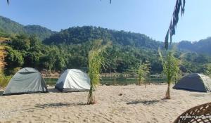 three tents on a beach next to a body of water at Dawki, Frankenstein adventure camp, riverside camping in Dawki