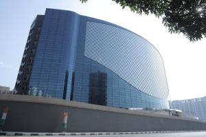 a large glass building with a reflection of a skyscraper at The World Surat in Surat