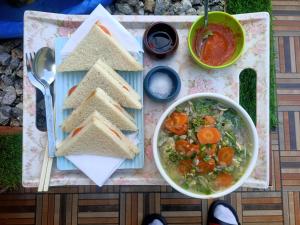 a table with a bowl of soup and a plate of sandwiches at Sunset Nest offbeat Homestay Perfect pause for Hikers in Darjeeling