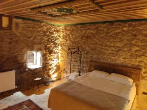 een slaapkamer met een bed in een stenen muur bij Euphoria Cave House in Nar