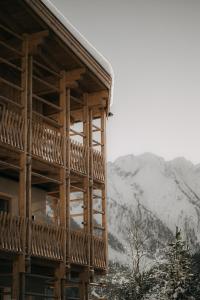 ein Holzgebäude mit Bergen im Hintergrund in der Unterkunft FRÄULEIN NANNERL - Boutique Aparthotel in Gerlos