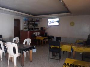 ein Esszimmer mit Tischen und Stühlen sowie einem TV in der Unterkunft RockVilla GuestHouse Njabini in South Kinangop