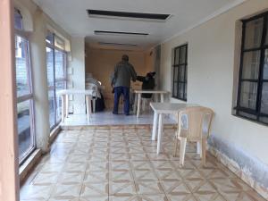 un uomo in piedi in una stanza con tavolo e sedie di RockVilla GuestHouse Njabini a South Kinangop