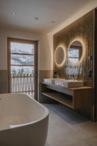 ein Badezimmer mit einer Badewanne, 2 Waschbecken und einem Spiegel in der Unterkunft FRÄULEIN NANNERL - Boutique Aparthotel in Gerlos