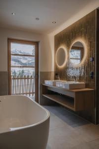 a bathroom with a tub and two sinks and a mirror at Haus Tyrol Gerlos in Gerlos