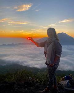 a woman standing on top of a mountain at sunset at jeep sunrise and trakking in Kintamani