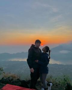 a man and a woman standing on top of a mountain at jeep sunrise and trakking in Kintamani