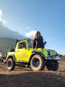 a woman sitting on the top of a monster truck at jeep sunrise and trakking in Kintamani