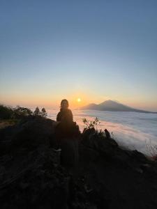 a person sitting on a hill watching the sunset at jeep sunrise and trakking in Kintamani