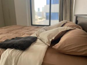 - un lit avec des oreillers et une couverture dans l'établissement Heart of Abu Dhabi - Adorable Master Room, à Abu Dhabi