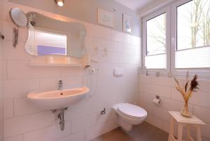 a white bathroom with a sink and a toilet at Hotel Garni Auszeit in Boltenhagen +43 photos