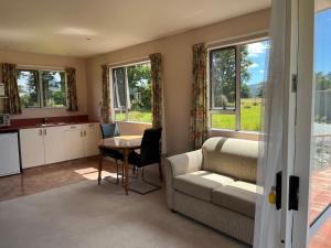 uma sala de estar com um sofá e uma mesa em Carrickfergus Cottage Unit 1 em Harihari