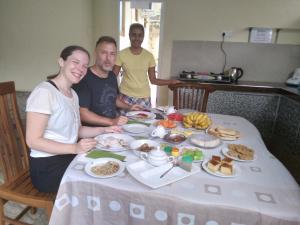 een groep mensen die rond een tafel zitten met eten bij Guillet Beach Home in Matara