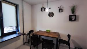 ein Esszimmer mit einem Tisch, Stühlen und einer Uhr in der Unterkunft Водопійна 25 CityRooms in Bila Zerkwa