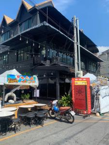 卡塔海灘的住宿－BT hotel Kata Beach，一座配有桌椅的建筑,前面停有一辆摩托车