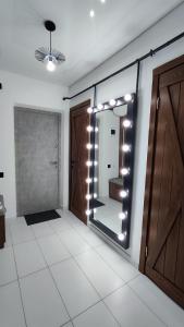 uma casa de banho com um espelho com luzes na parede em Водопійна 25 CityRooms em Bila Tserkva