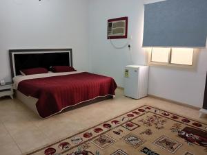Soma Suites في المدينة المنورة: غرفة نوم بسرير وبطانية حمراء وسجادة