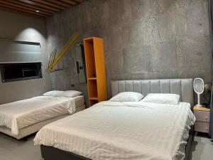 a bedroom with two beds and a concrete wall at MAYHOME Ninh Chu - Phòng đôi lớn in Bắc Sớn