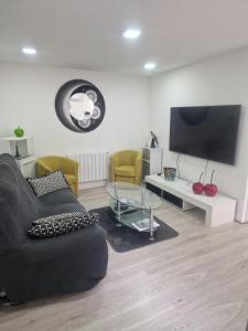 a living room with a black couch and a tv at MAISON CLIMATISEE ,2 CHAMBRES, PARKING compris in La Ciotat