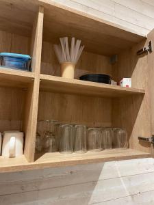 una estantería de madera con vasos y utensilios. en Le petit bois - parking privé, en Éveux