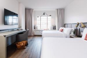 a hotel room with two beds and a television at The Alida, Savannah, a Tribute Portfolio Hotel in Savannah