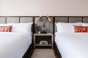 two beds with white sheets and a lamp on a night stand at The Alida, Savannah, a Tribute Portfolio Hotel in Savannah