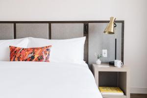 a bedroom with a white bed with a lamp and a side table at The Alida, Savannah, a Tribute Portfolio Hotel in Savannah