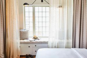 a window seat in a bedroom with a window with a book at The Alida, Savannah, a Tribute Portfolio Hotel in Savannah