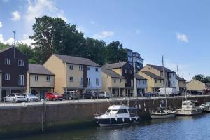 a boat is docked in the water next to houses at Peaceful marina-side house in north Wales in Caernarfon