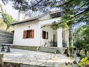 a white house with a balcony and a patio at Forest cottage top of the world in Vourgareli +33 photos