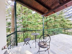 a patio with two chairs and a table on a balcony at Forest cottage top of the world in Vourgareli