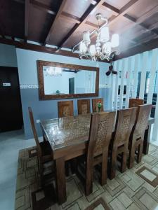 einen Esstisch mit Holzstühlen und einem Spiegel in der Unterkunft Kuantan Nadira Suite Homestay in Kuantan