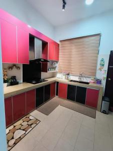 eine Küche mit roten und schwarzen Schränken und einem Waschbecken in der Unterkunft Kuantan Nadira Suite Homestay in Kuantan