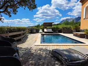 a swimming pool on a wooden deck with mountains in the background at Maison d'hôtes la Garenne in Puyloubier