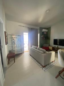 sala de estar con sofá blanco y TV en Apartamento em condomínio de luxo próximo à praia, en Porto Seguro