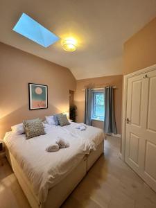 a bedroom with a large white bed with a skylight at Spring Cottage, Little Haven, a minute from beach in Little Haven