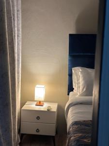 a bed and a nightstand with a lamp on it at Shiloh Inn in Gaborone