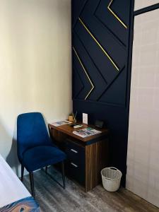 a bedroom with a desk and a blue chair at Shiloh Inn in Gaborone