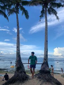 a man walking between two palm trees on the beach at Dadods homestay in General Luna