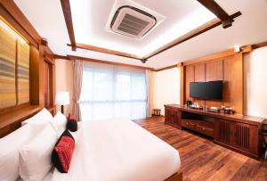 - une chambre avec un grand lit et une télévision dans l'établissement Phra Singh Village, à Chiang Mai