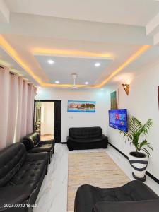 uma sala de estar com sofás de couro preto e uma televisão em Ayaa Luxury Apartment 4th Floor Zanzibar em Zanzibar
