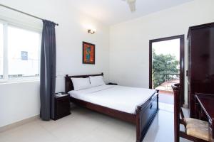Sanctum Suites Indiranagar Bangalore في بانغالور: غرفة نوم بسرير وشرفة