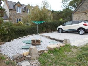 een auto geparkeerd op een oprit met een speeltuin bij La Petite Maison, idéal pour velo,pied,peche,relax in Mur-de-Bretagne