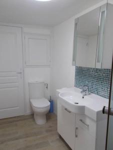 La salle de bains blanche est pourvue de toilettes et d'un lavabo. dans l'établissement La Petite Maison, idéal pour velo,pied,peche,relax, à Mûr-de-Bretagne