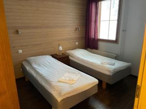 two twin beds in a room with a window at Viihtyisä lomahuoneisto Rukalla! in Kuusamo