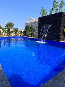 a large blue swimming pool with a waterfall at Hidden beach stay in Chennai